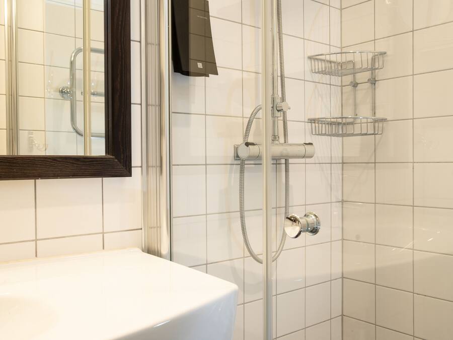 Une salle de bain avec un lavabo blanc, une douche en verre et un miroir.
