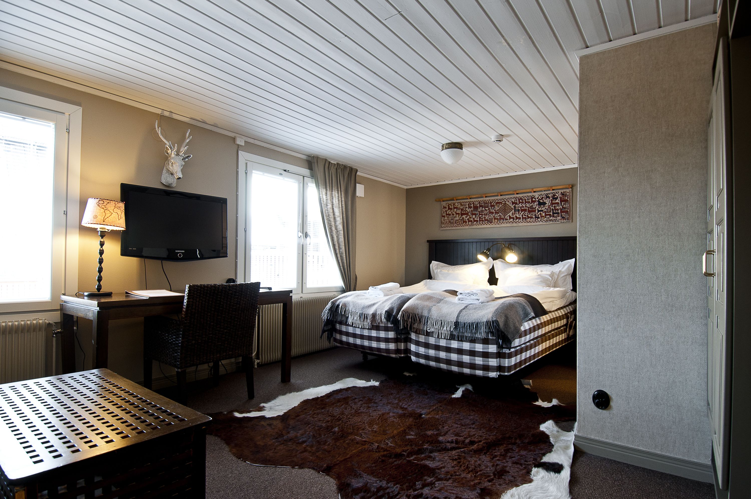 Een slaapkamer met een bed, een bureau, een televisie en een kussen van runderleer.
