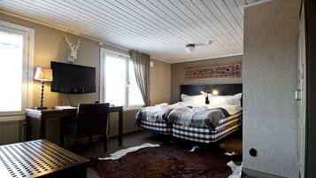 Een slaapkamer met een bed, een bureau, een televisie en een kussen van runderleer.