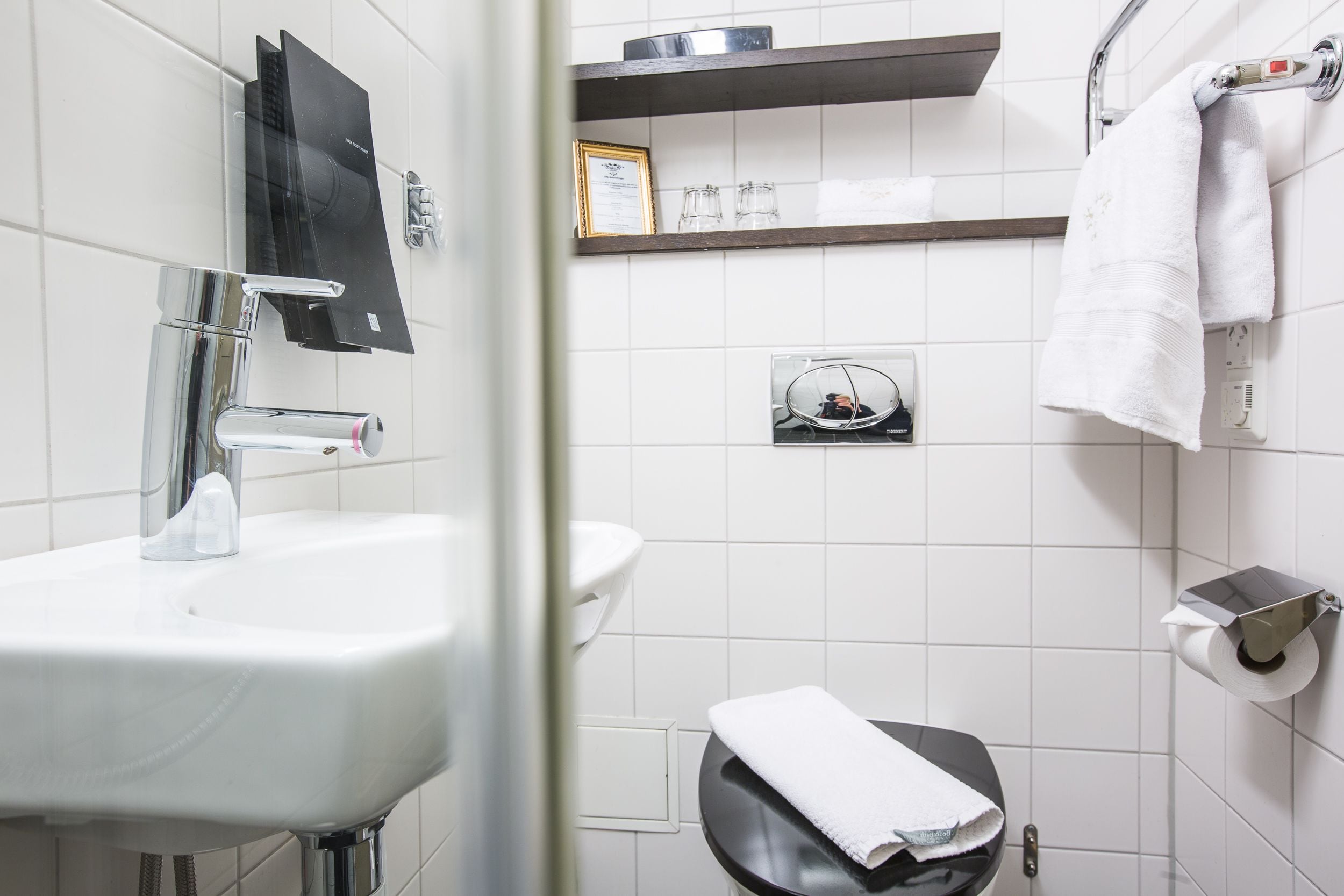 Un baño con un lavamanos blanco, un espejo, un perchero para toallas y un inodoro.