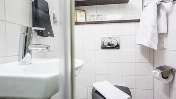 Un baño con un lavamanos blanco, un espejo, un perchero para toallas y un inodoro.