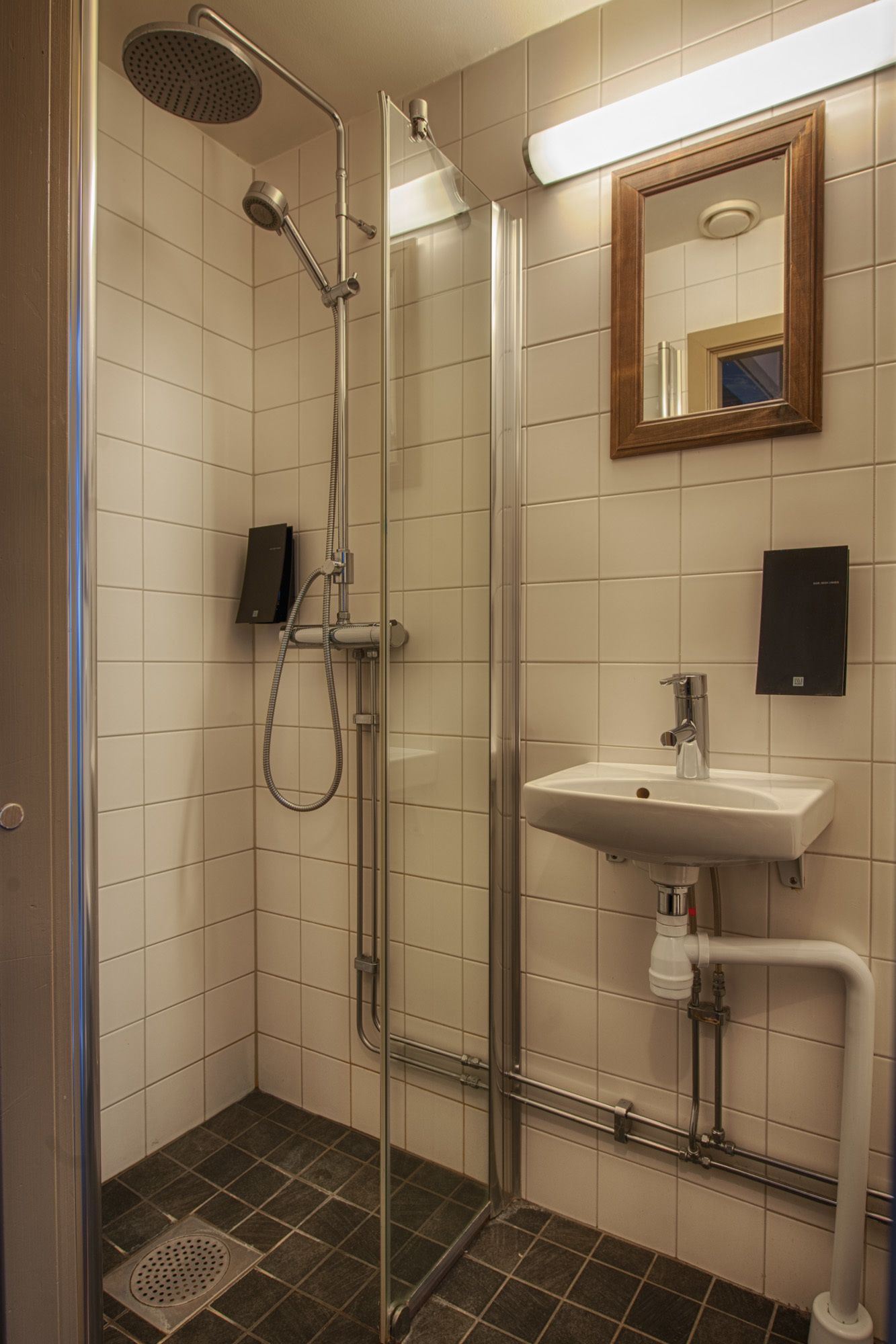 A glass-enclosed shower with a handheld showerhead and a wall-mounted faucet.