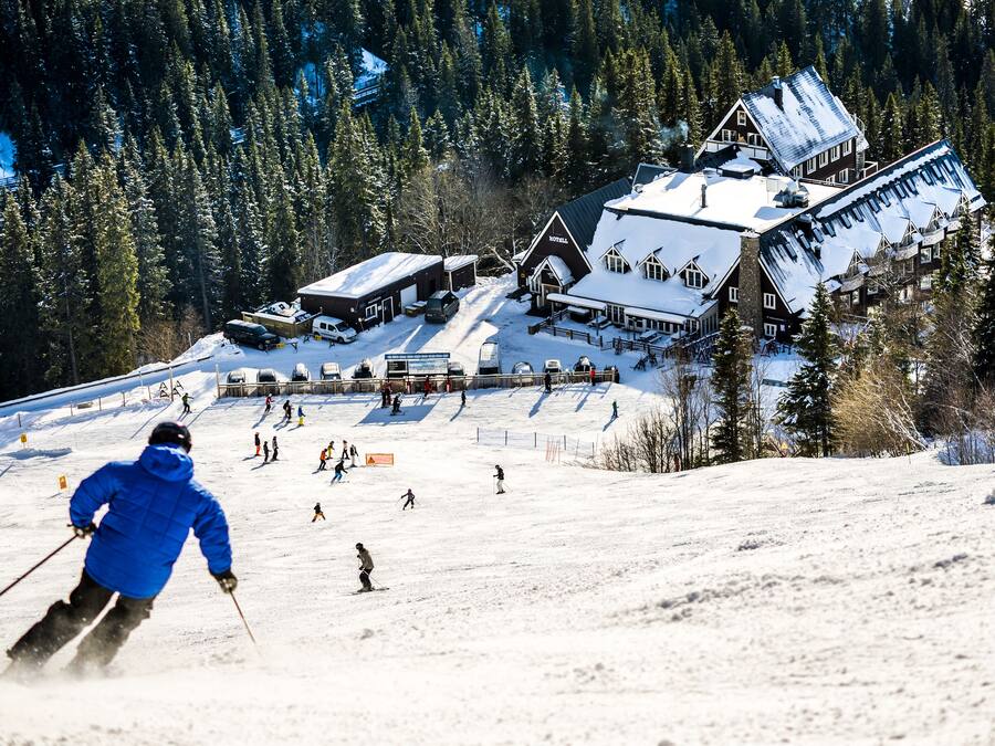 Una stazione sciistica con un ampio albergo, piste da sci e una montagna sullo sfondo.
