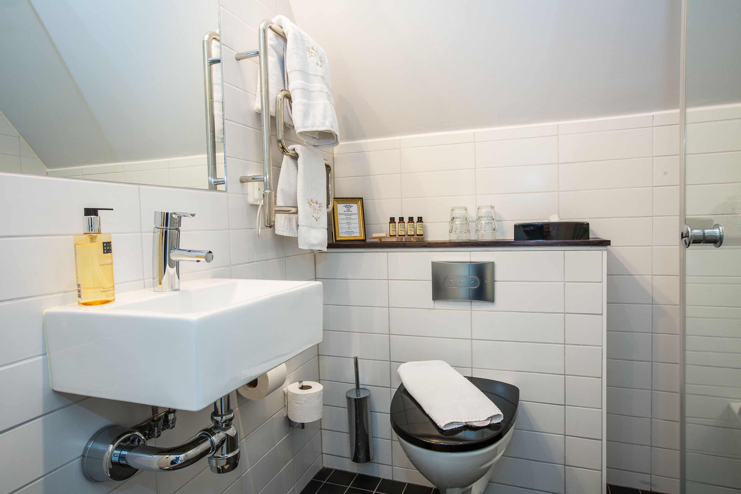Un baño moderno con lavamanos, inodoro y zona de ducha blancos.