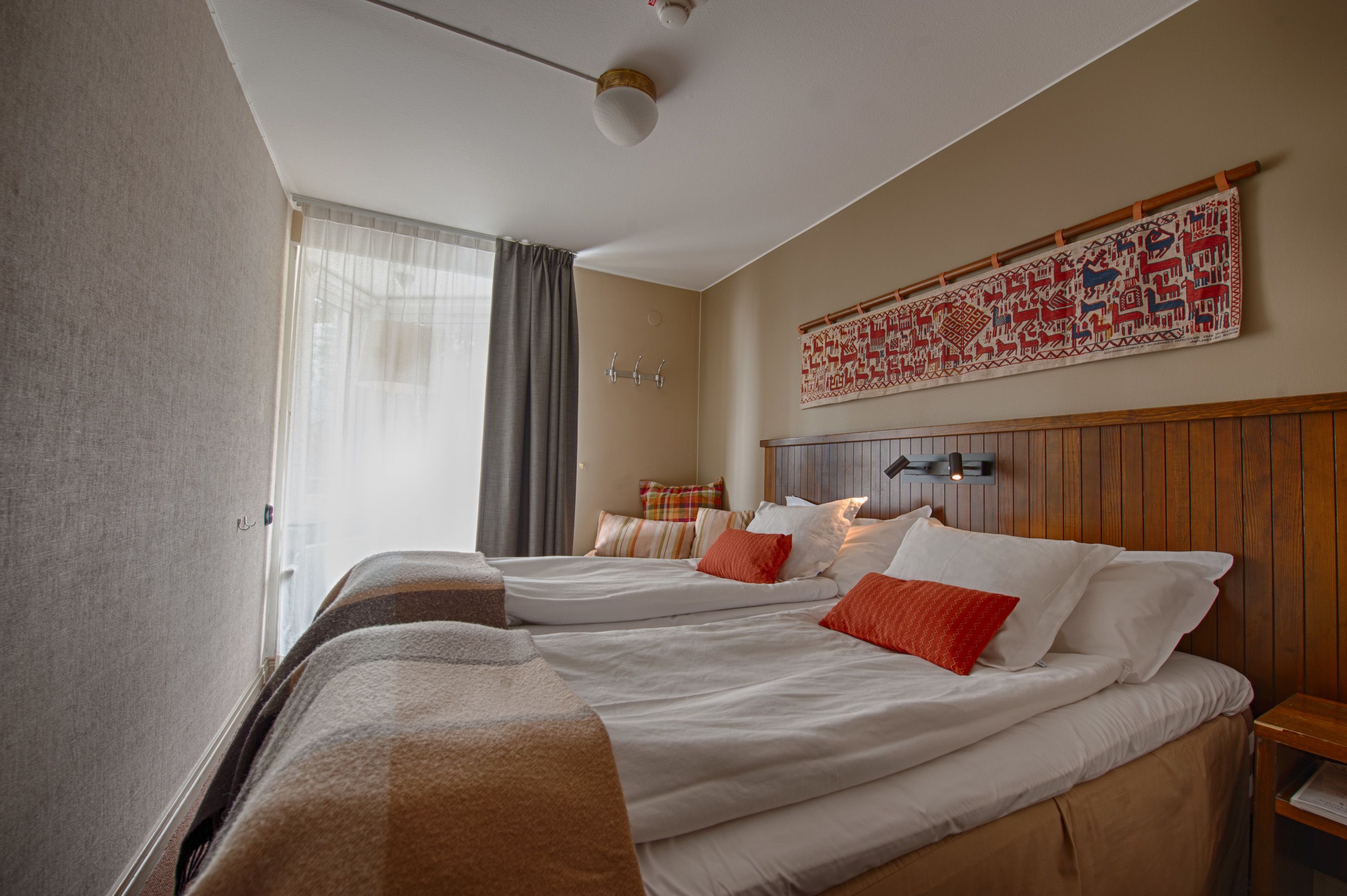 A hotel room with two beds, a large tapestry on the wall, and a wooden headboard.
