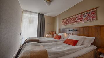 A hotel room with two beds, a large tapestry on the wall, and a wooden headboard.