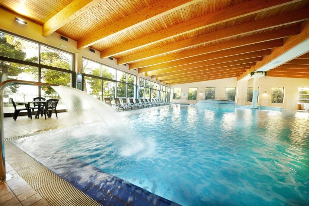Una piscina techada, una piscina al aire libre de temporada, sombrillas