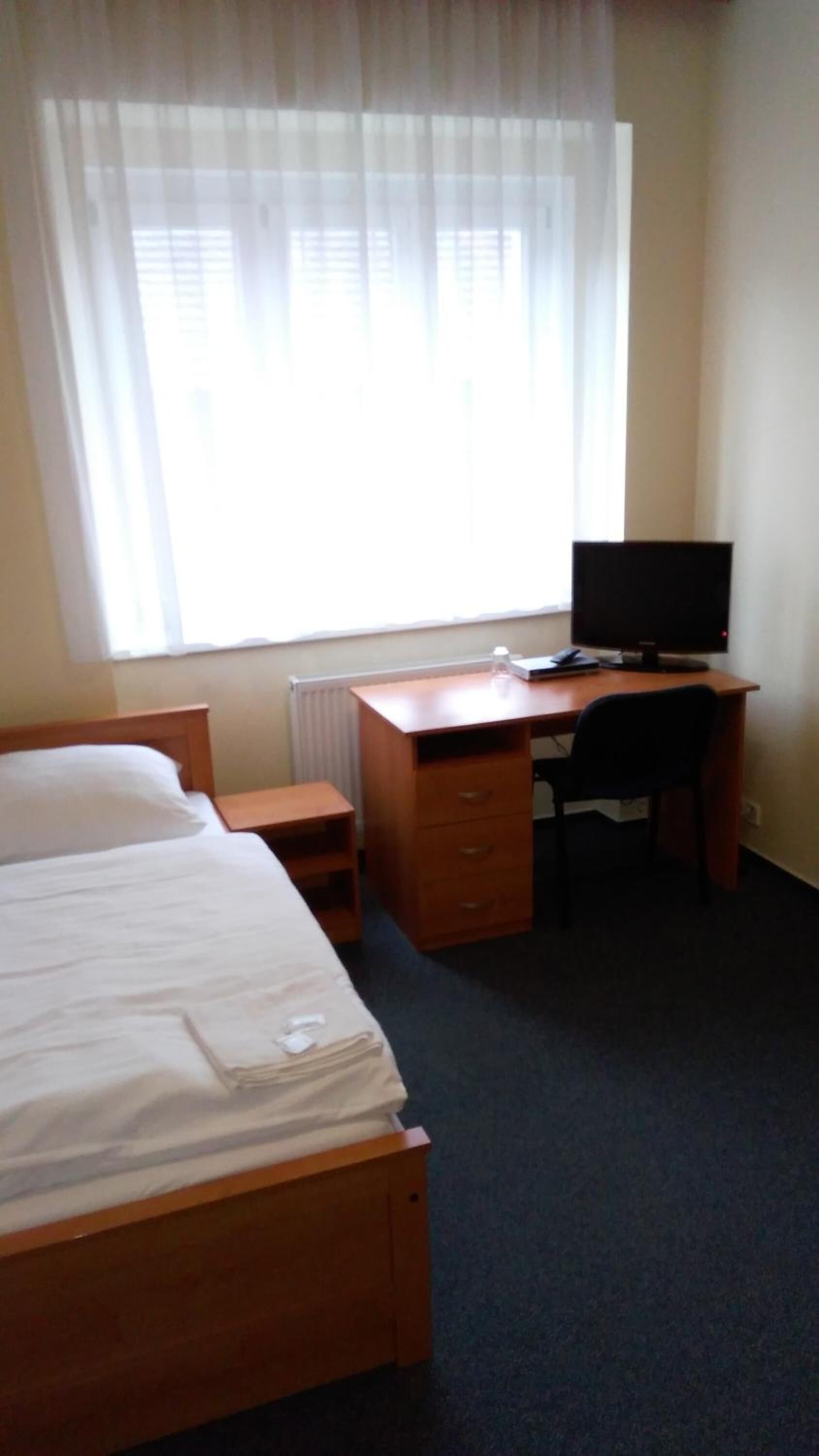 Une chambre d’hôtel avec un lit, un bureau, une chaise et un téléviseur.