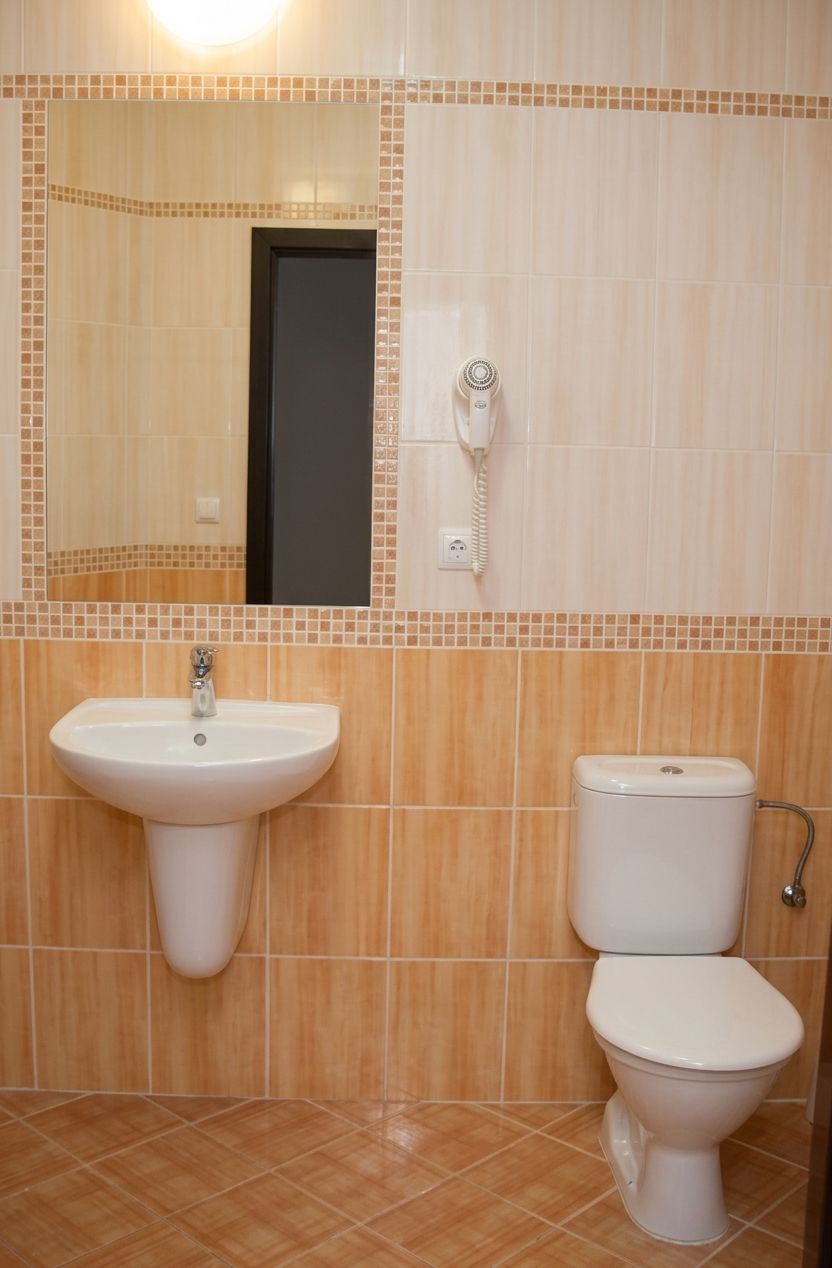 A bathroom with a sink, toilet, and a mirror.