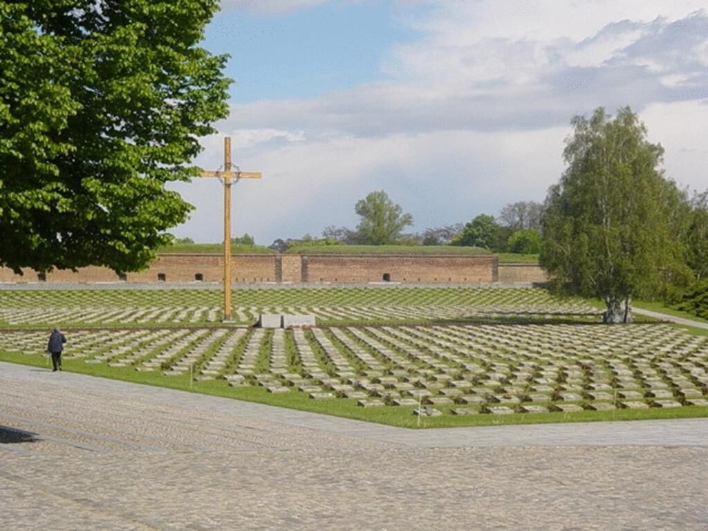 A cemetery with rows of graves and a wooden cross in the center.