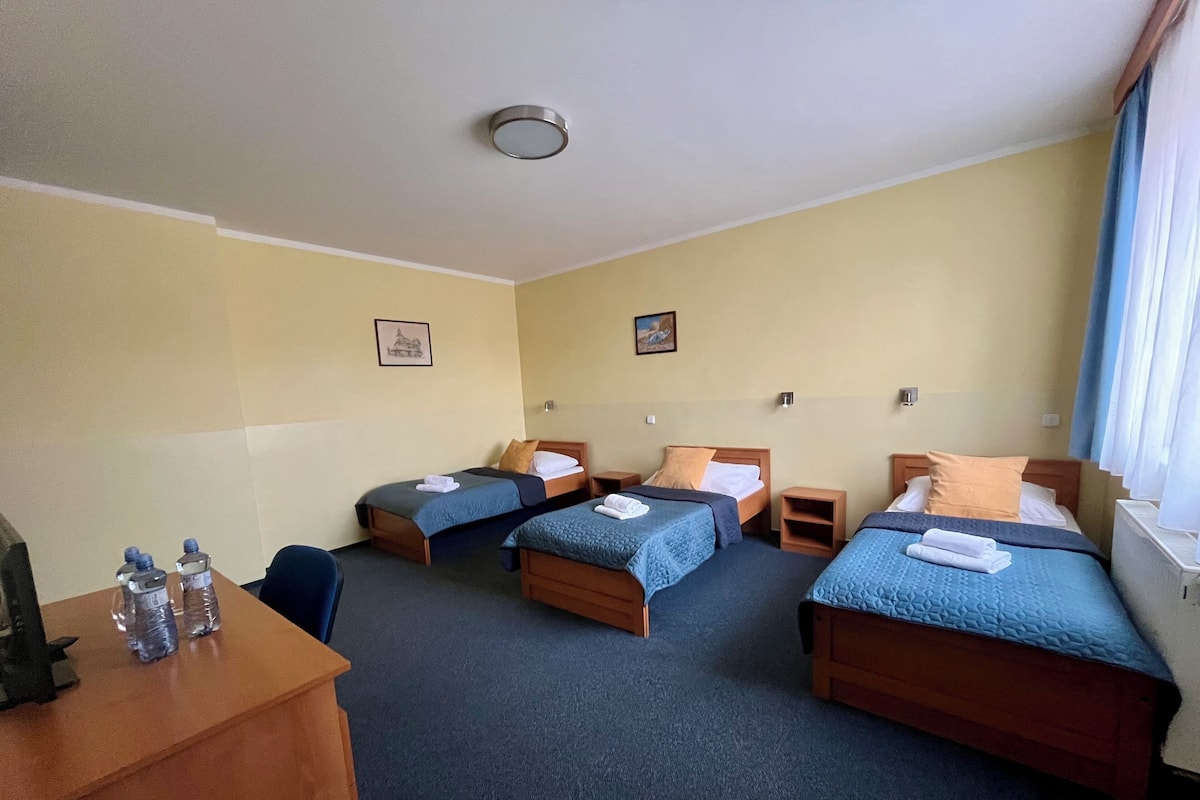 A hotel room with two beds, a desk, and a chair.