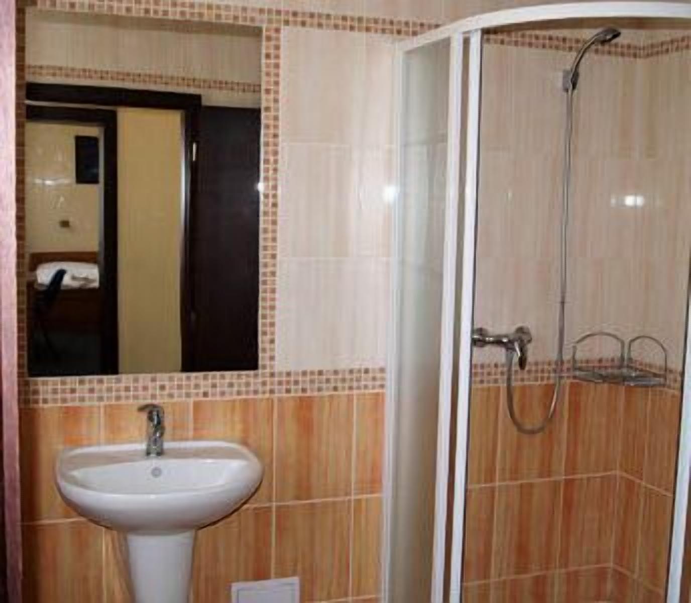 Un baño con lavamanos, espejo y ducha.