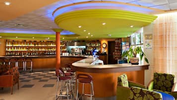 A bar area with stools, a counter, and shelves with bottles.