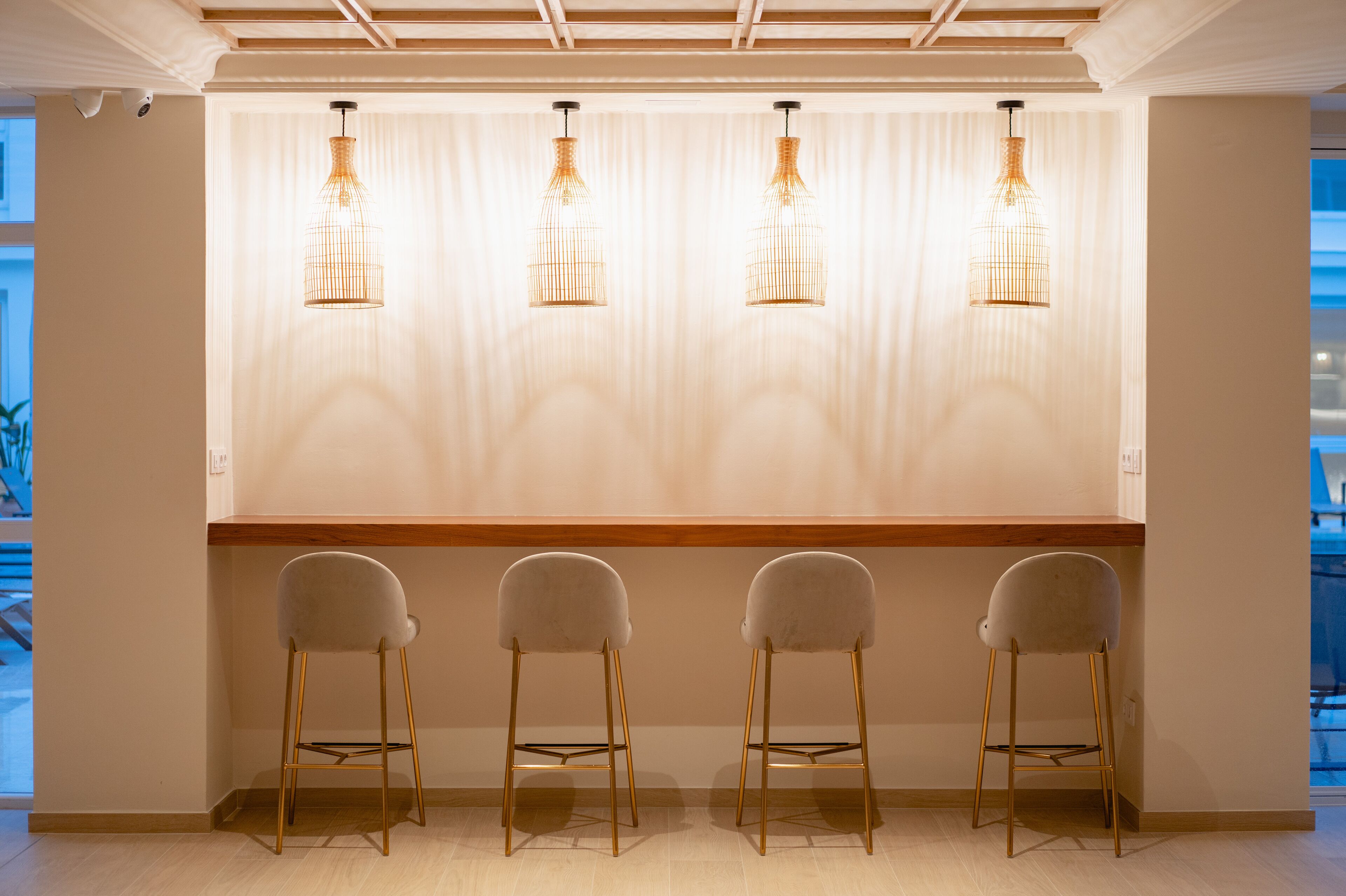 Una zona de bar con cuatro taburetes y luces colgantes.