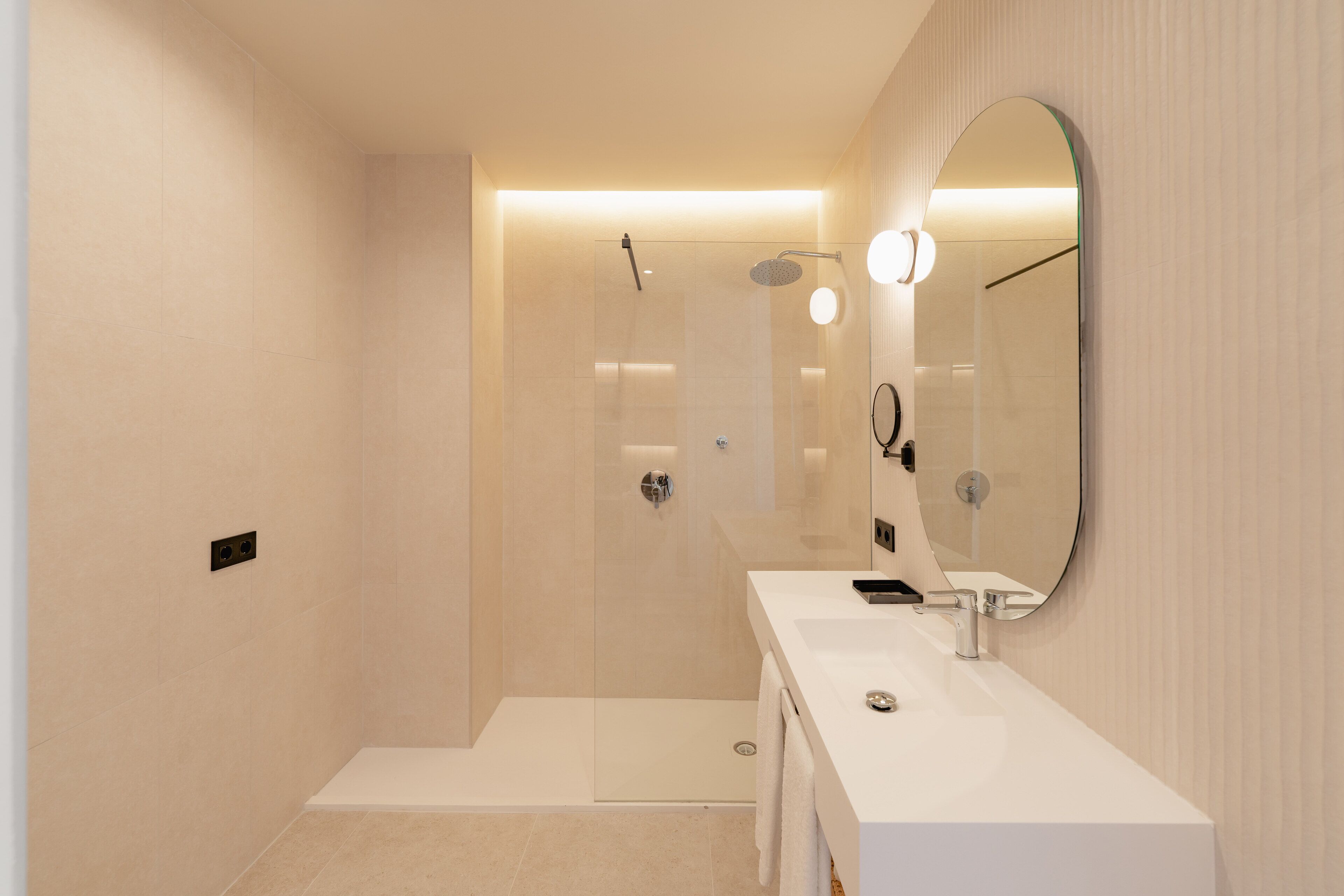 A modern bathroom with a glass-enclosed shower, a white sink, and a large mirror.