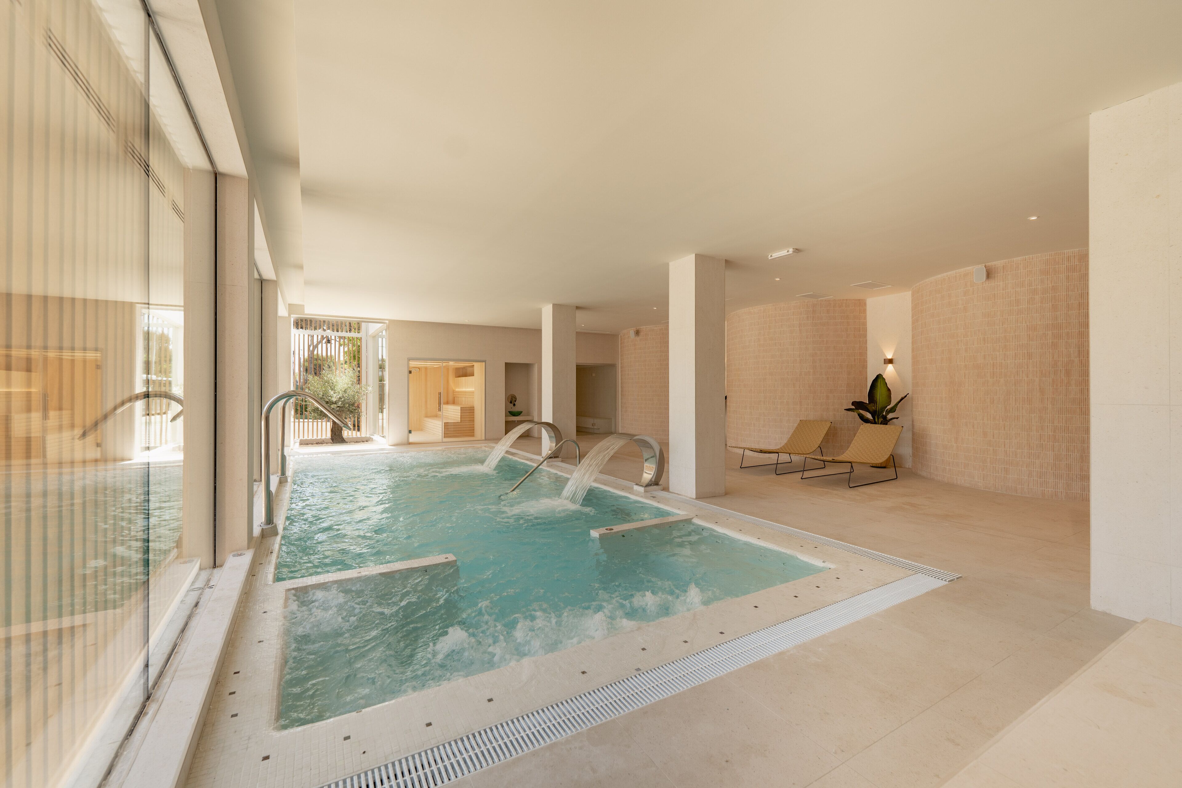 En inomhuspool med klart vatten, omgiven av beige väggar och ett kaklat golv.