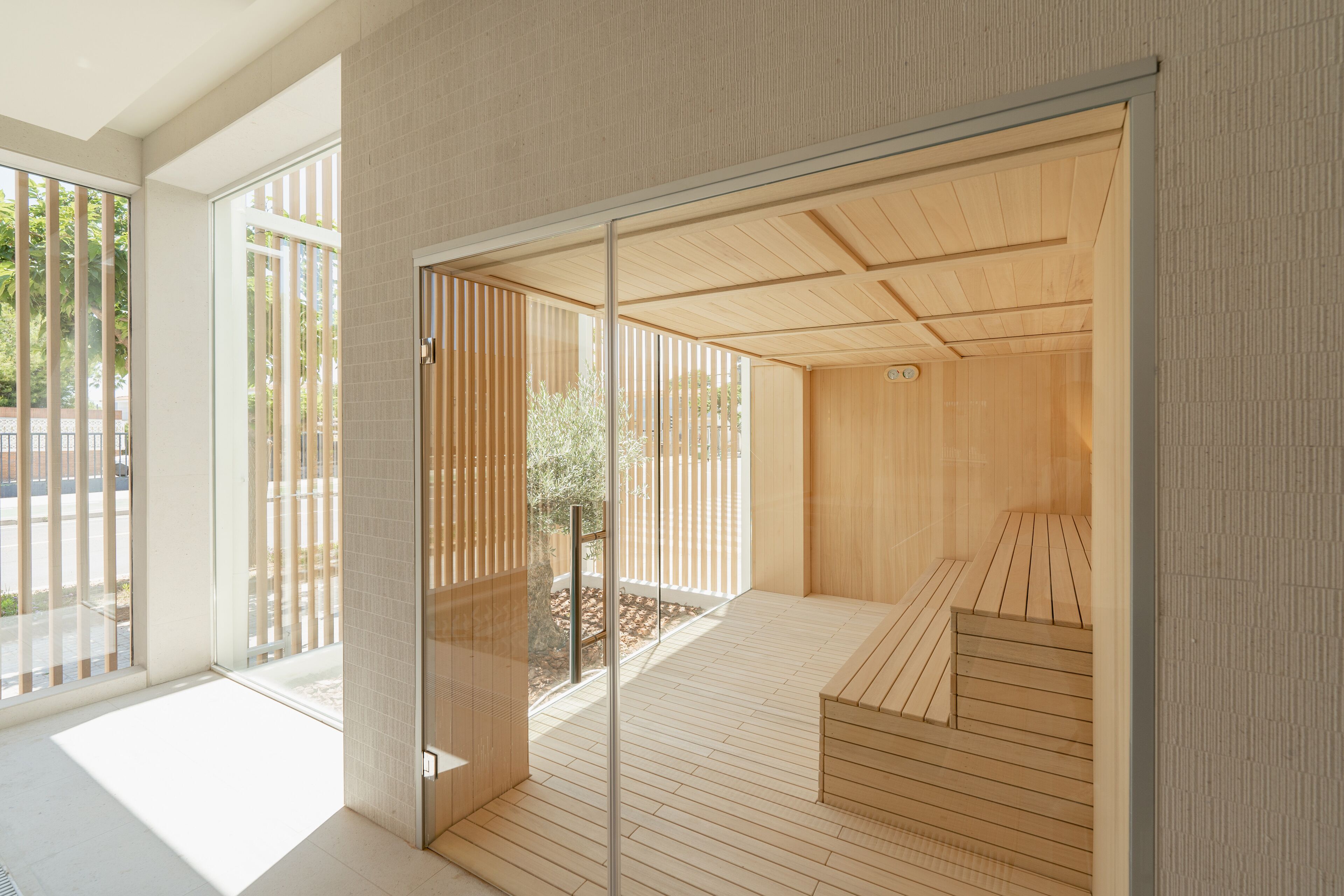Ein moderner Wellnessraum mit Holzboden, Glastüren und Blick ins Freie.