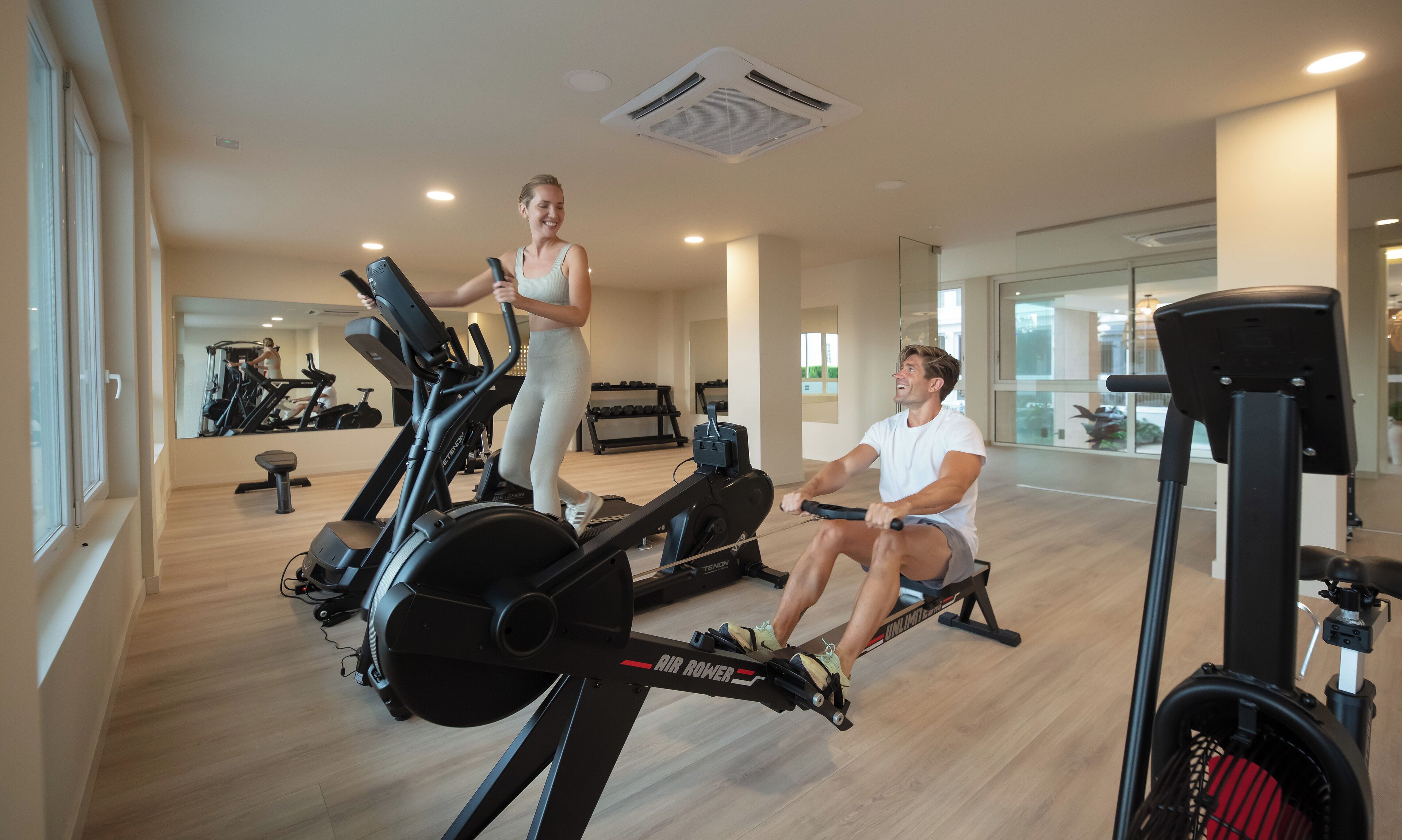 Una palestra moderna con attrezzature cardio, uno specchio a parete e un ambiente spazioso.