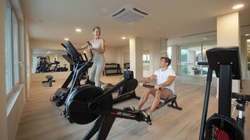 Una palestra moderna con attrezzature cardio, uno specchio a parete e un ambiente spazioso.