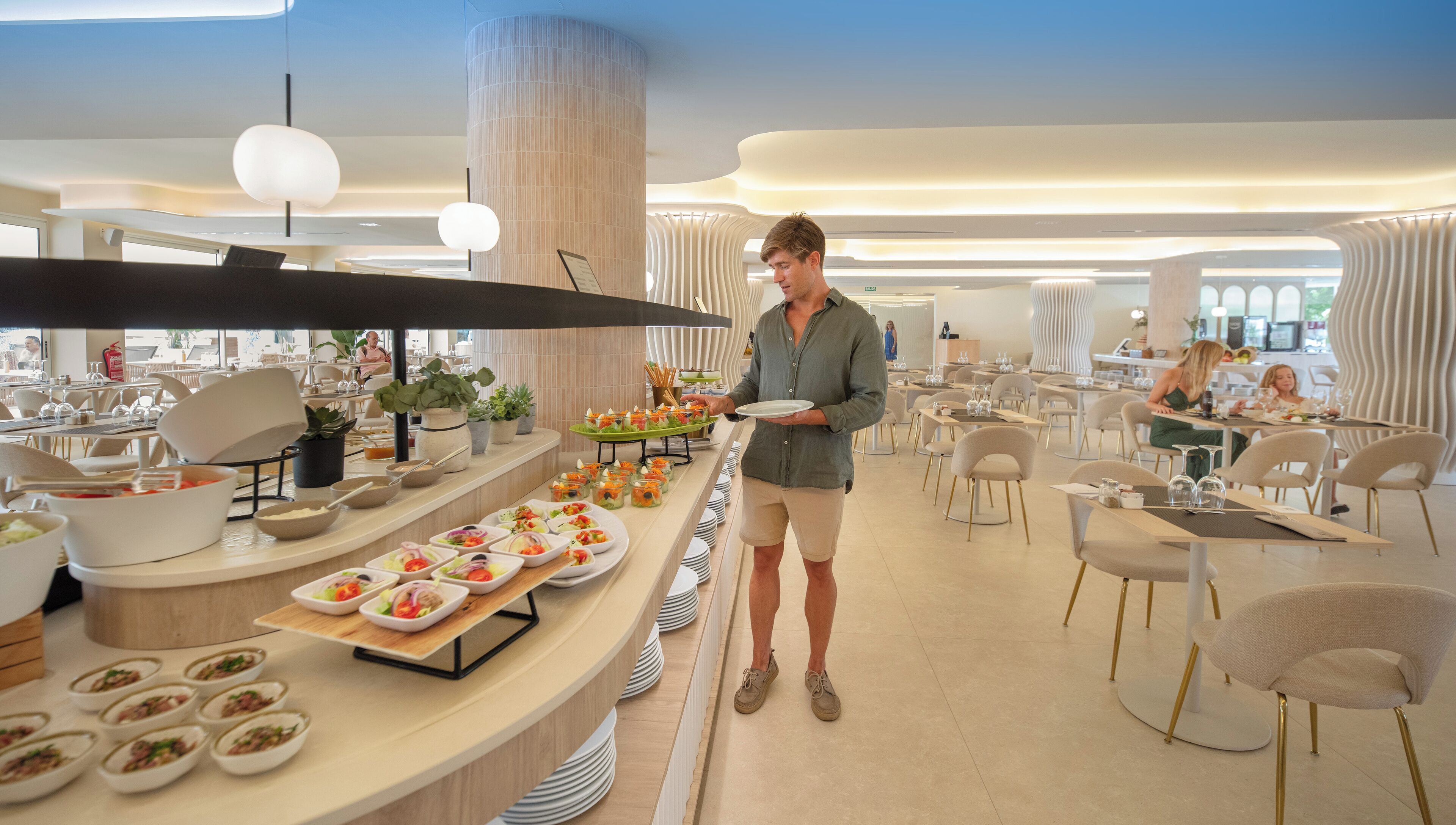 Un espace de restauration moderne dans un hôtel, avec un buffet proposant différents stands de nourriture et diverses options d’aménagement pour les places assises.