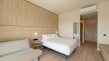 Une chambre d’hôtel moderne équipée d’un lit, d’un canapé, d’une petite table et d’un miroir.