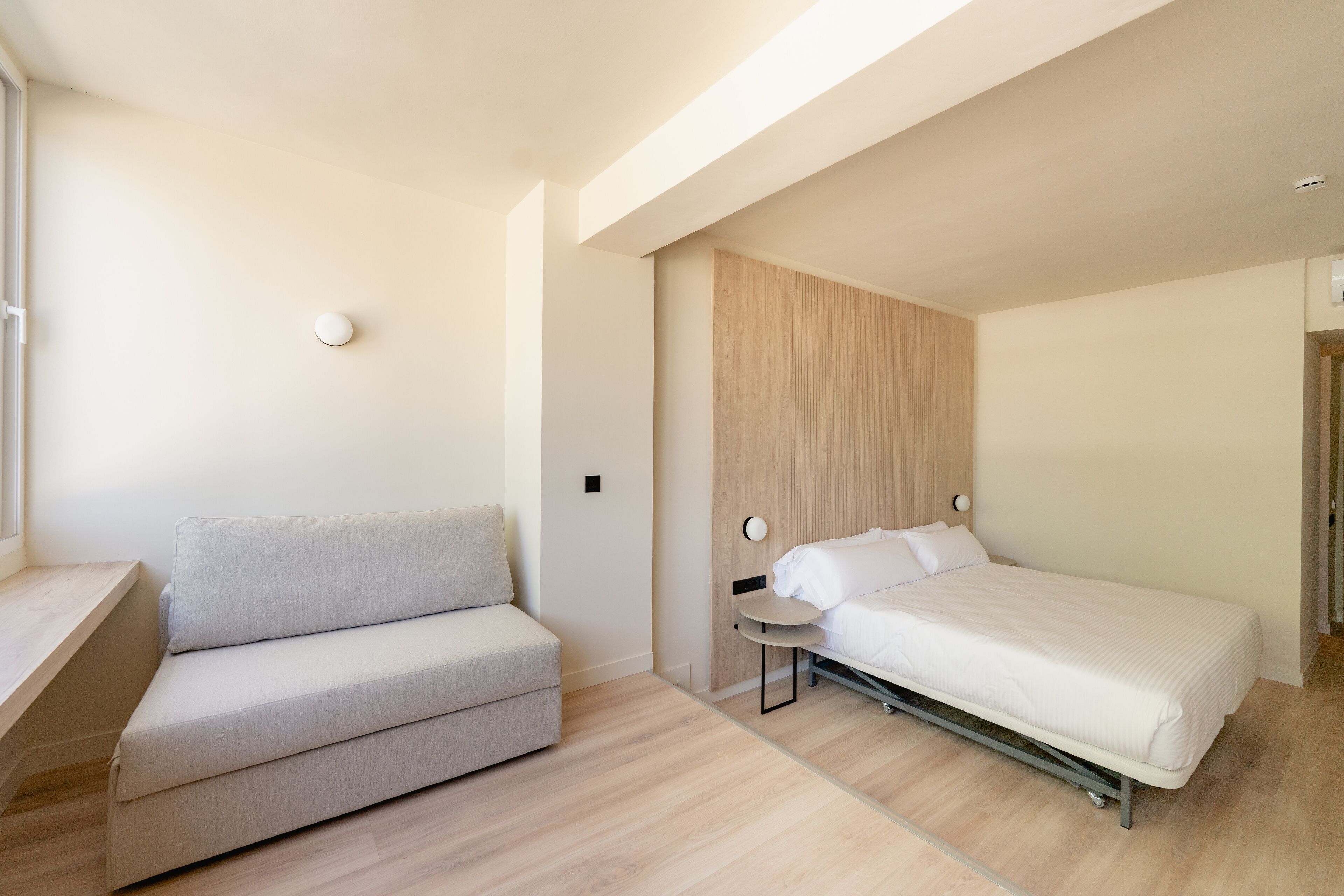 A modern bedroom with a sofa, a bed, and a small table.