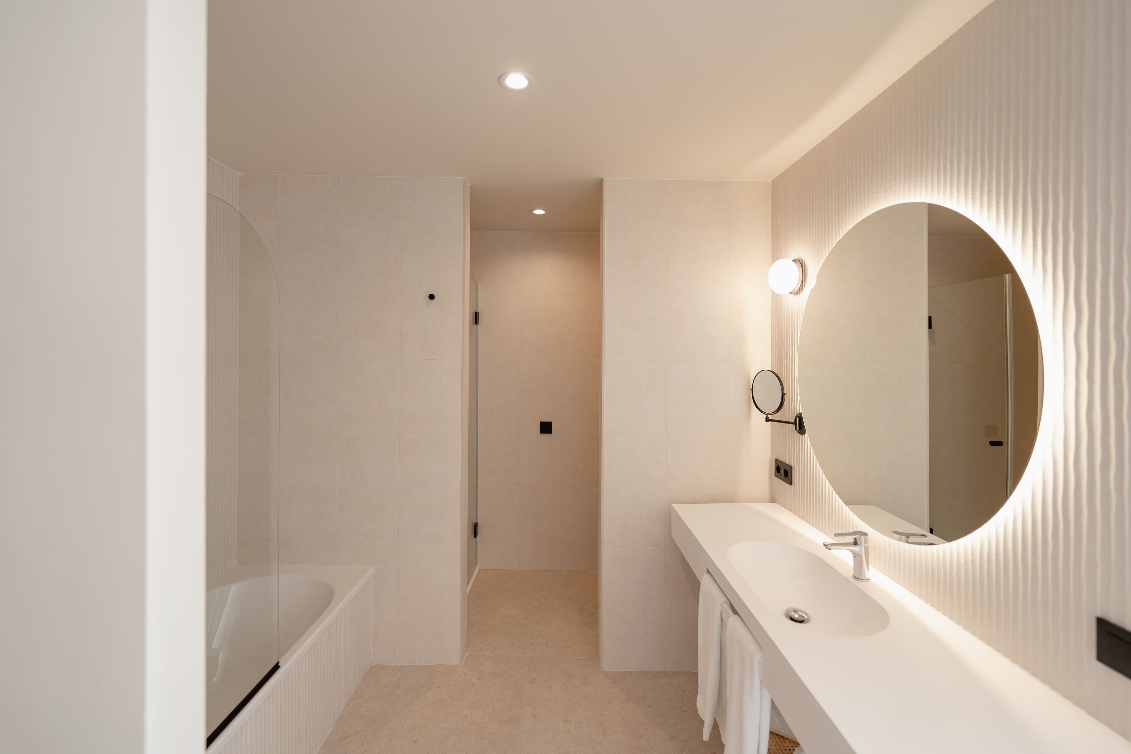 A modern bathroom with a large mirror, a bathtub, and a vanity with a sink.