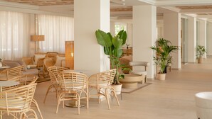 Een ruime lobby met rieten meubels, potplanten en een modern plafondontwerp.
