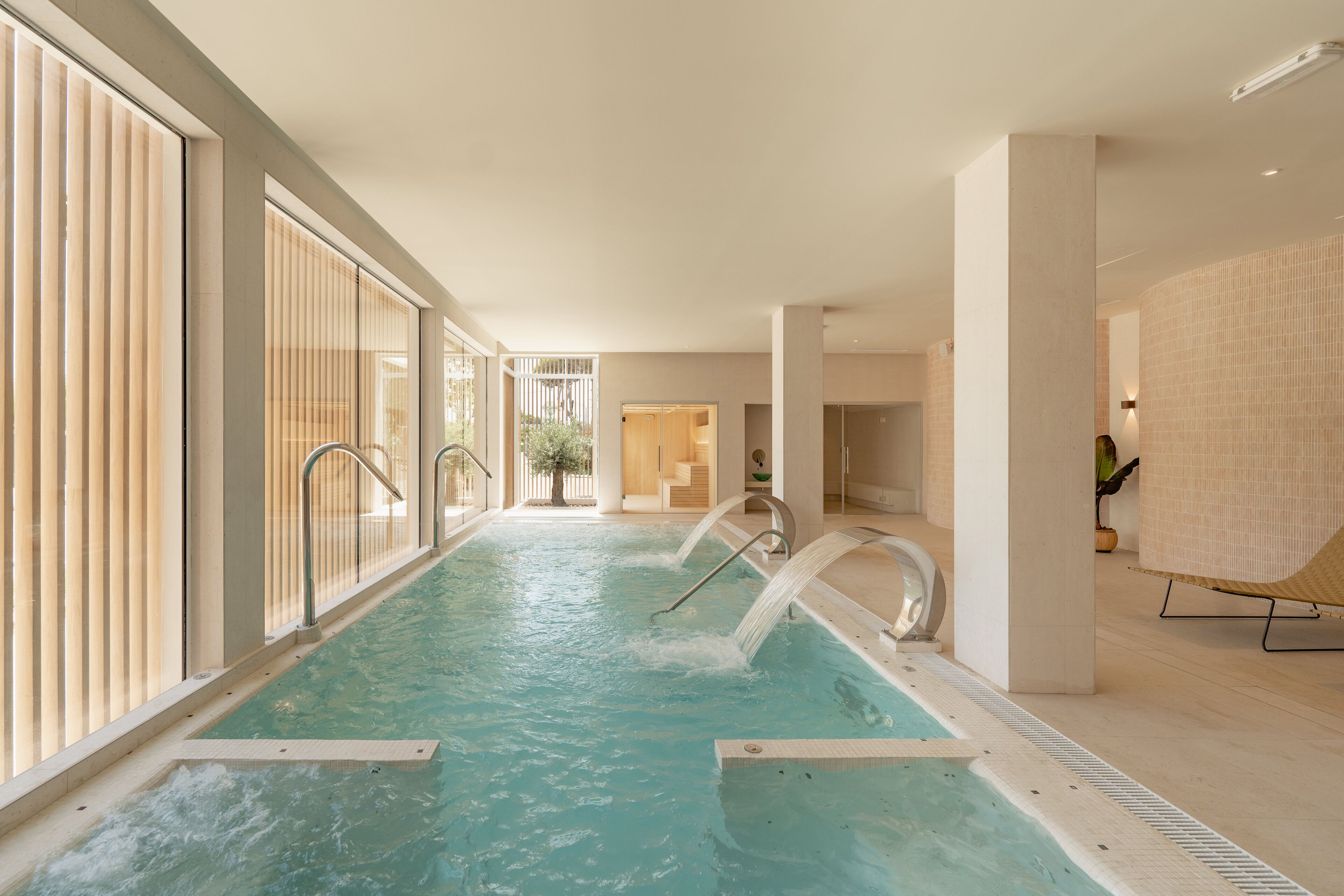 Una piscina con agua cristalina, rodeada de amplios ventanales y un diseño interior moderno.