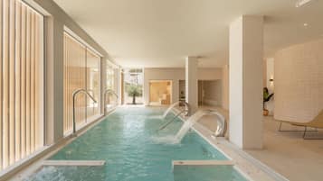 Una piscina con agua cristalina, rodeada de amplios ventanales y un diseño interior moderno.