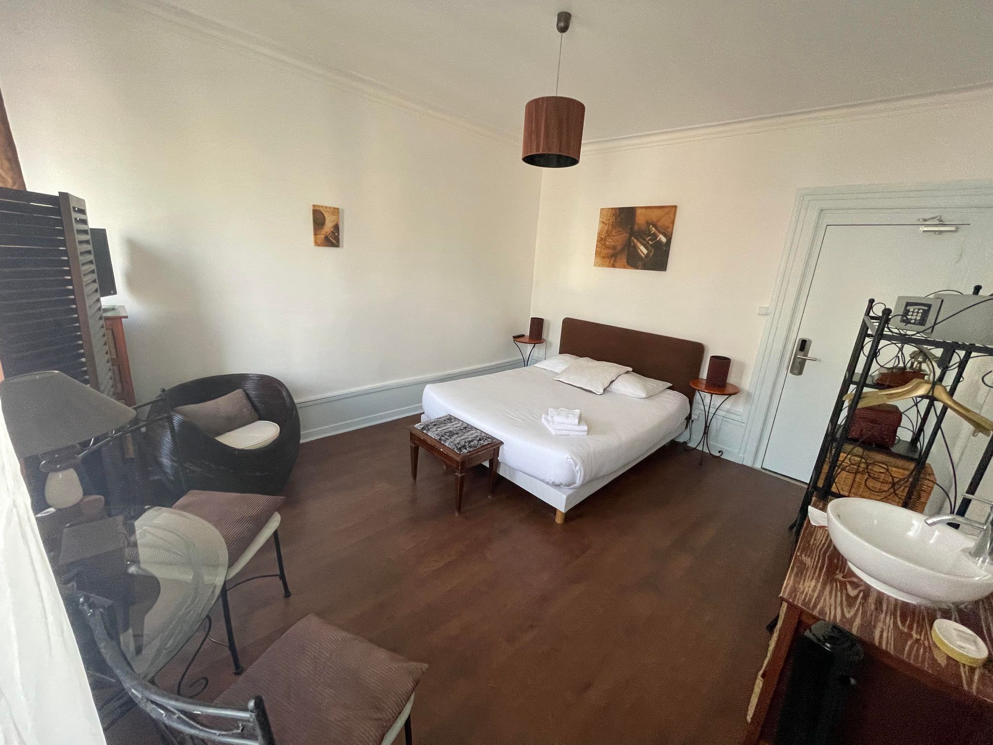 Une chambre à coucher comprenant un lit, des tables de chevet, une chaise, un bureau et une salle de bain avec un lavabo.