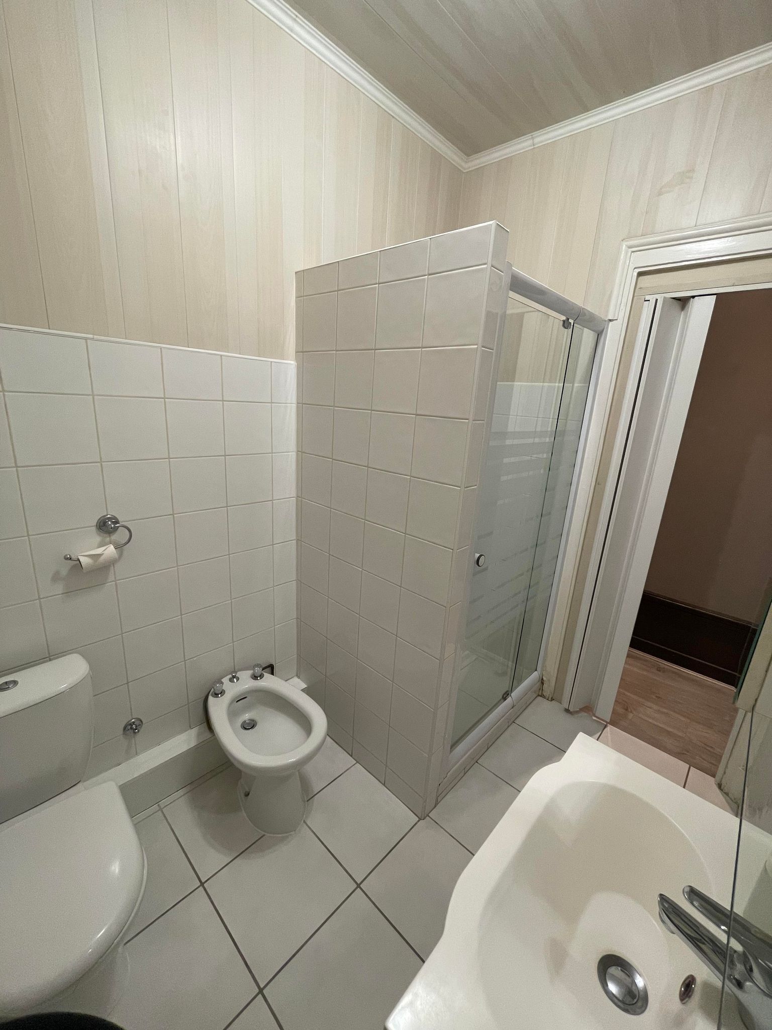 Casa de banho com sanita, bidé e zona de duche separada por vidro.