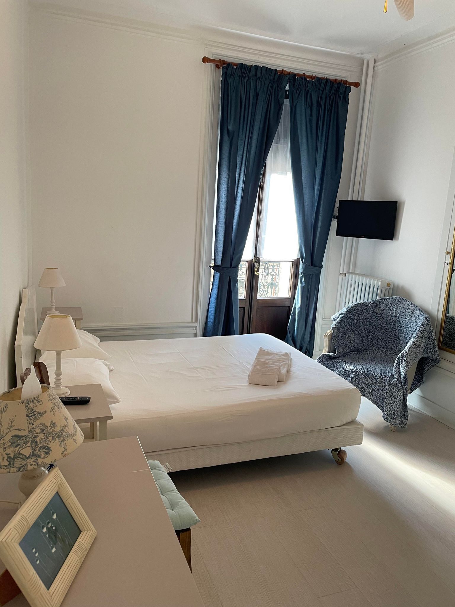 Een hotelkamer met een bed, een bureau met een lamp, een stoel, een televisie en een raam met gordijnen.