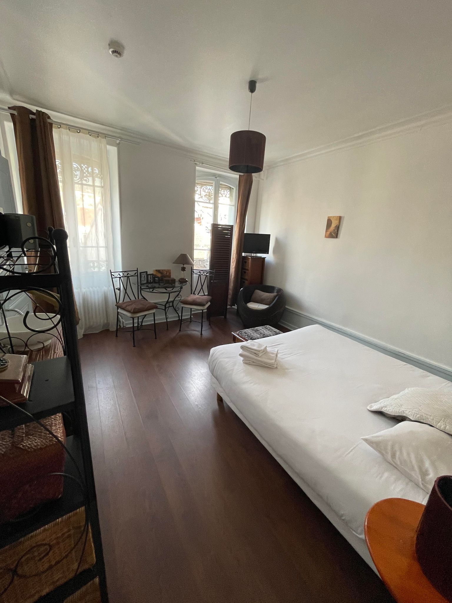 Habitación de hotel con cama, escritorio, silla, televisor y ventana con cortinas.