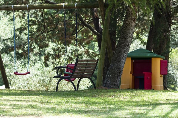 Un parque con un columpio, un banco y una casita de juegos.