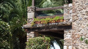A stone balcony with wooden railings, lush green foliage, and potted plants. - Casale Aronne (Massa Marittima)