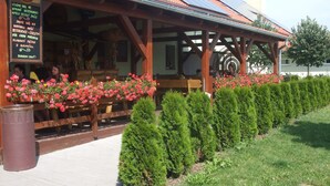 Un restaurante con zona de estar cubierta al aire libre, paneles solares en el techo y setos bien cuidados a lo largo del sendero.