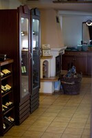 A room with a wine rack, a cabinet with glass doors, a wicker basket, and a tiled floor.