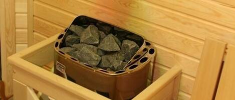 Un sauna aux murs en bois, doté d’un luminaire suspendu et d’un banc en bois.