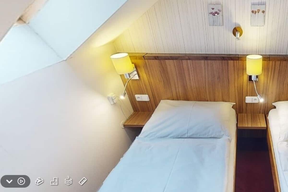 A hotel room with two beds, wooden headboard, bedside lamps, and a small wall decoration.