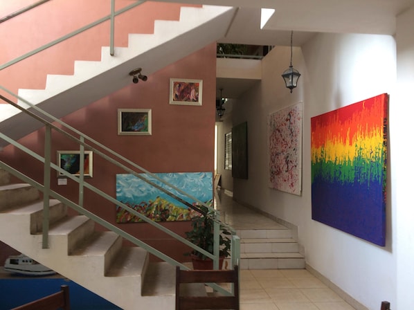 A staircase with a metal railing, a painting on the wall, and a potted plant.