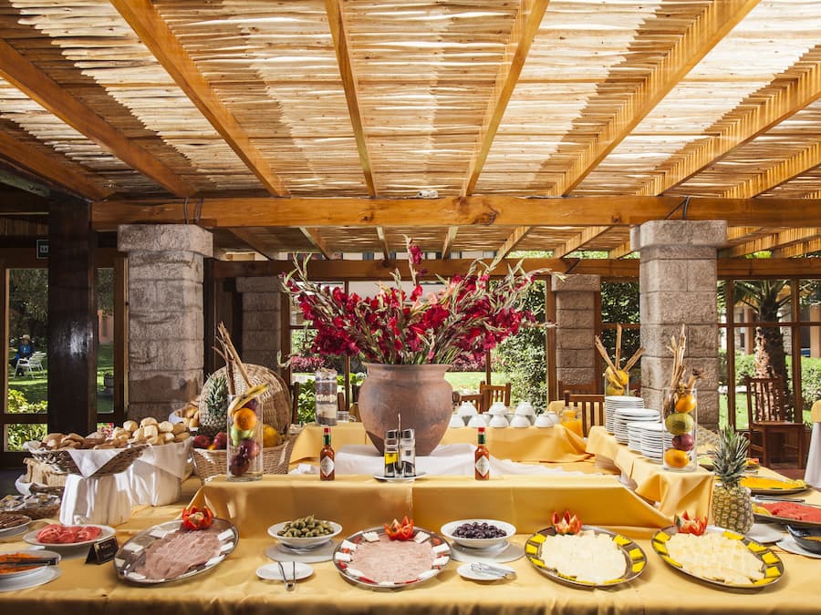 Una mesa de buffet con diversos alimentos y un gran jarrón de flores.