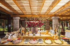 A buffet table with various food items and a large vase of flowers.