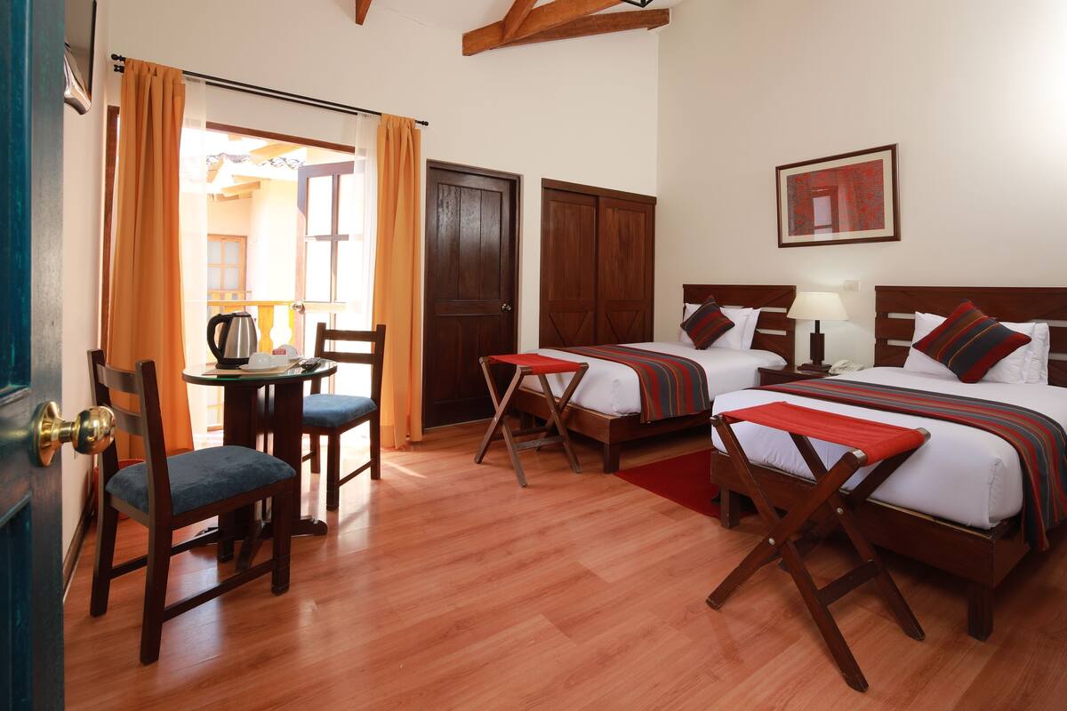Ein Hotelzimmer mit zwei Betten, einem Schreibtisch, einem Stuhl und einem Tisch.