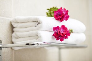 A stack of white towels on a metal tray with a white wall in the background.