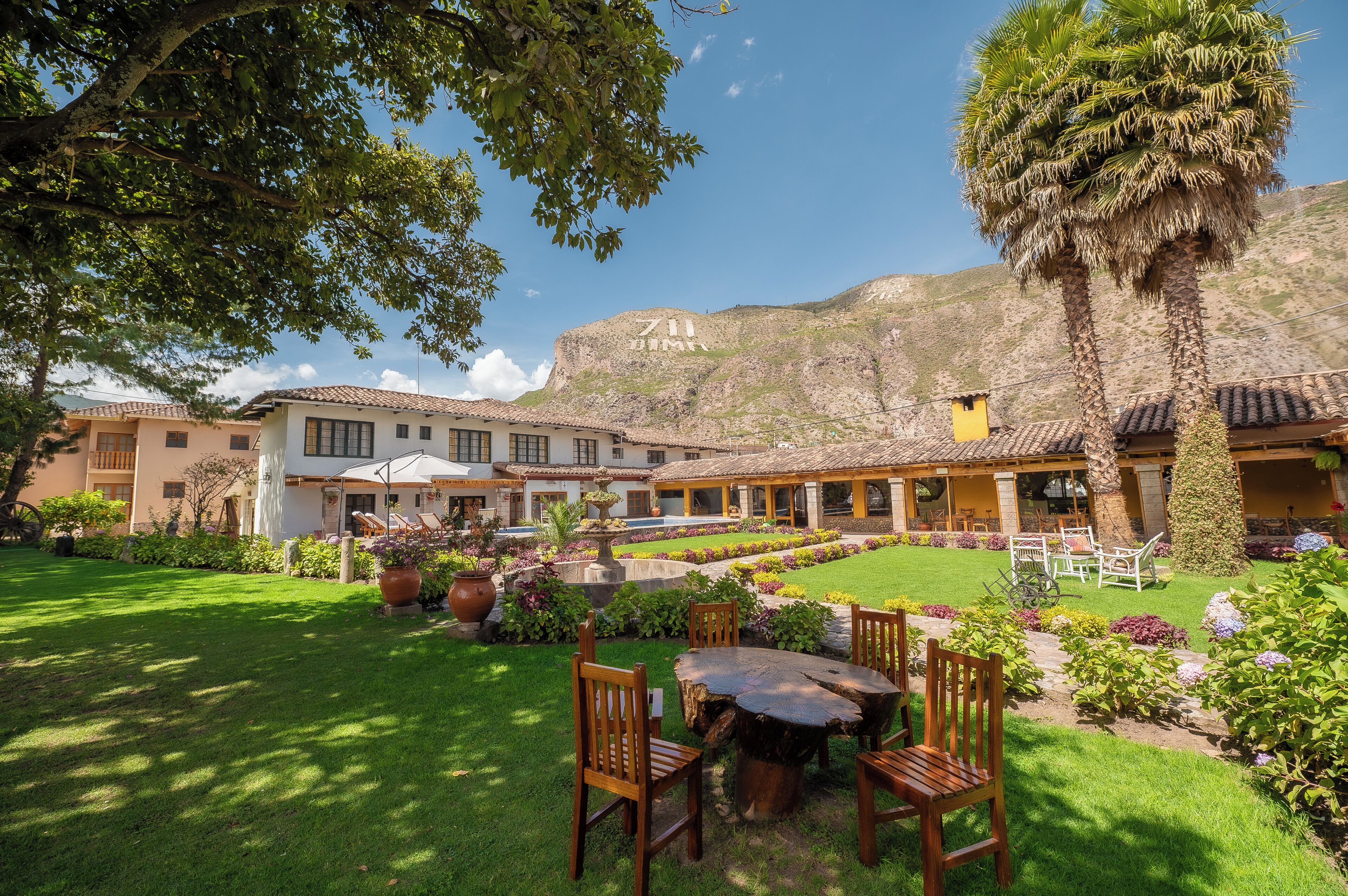 A courtyard with a dining area, outdoor seating, and a mountain backdrop.