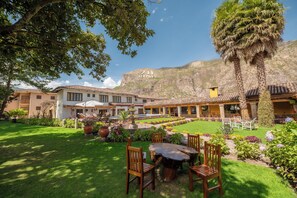 A courtyard with a dining area, outdoor seating, and a mountain backdrop. - San Agustin Urubamba & Spa (Urubamba)
