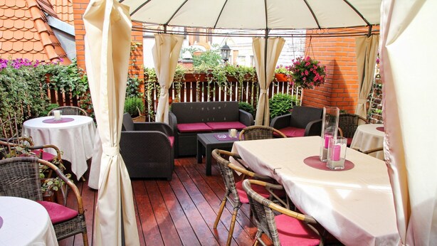 An outdoor patio with wicker furniture, a white tablecloth, and a brick wall in the background.