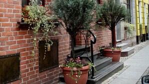 A hotel with a red brick facade, a sign reading "HOTEL GOTYRK", and potted plants on the sidewalk.
