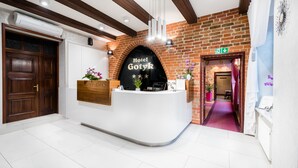 A hotel reception area with a modern design, featuring a reception desk, a brick wall, and a wooden ceiling.